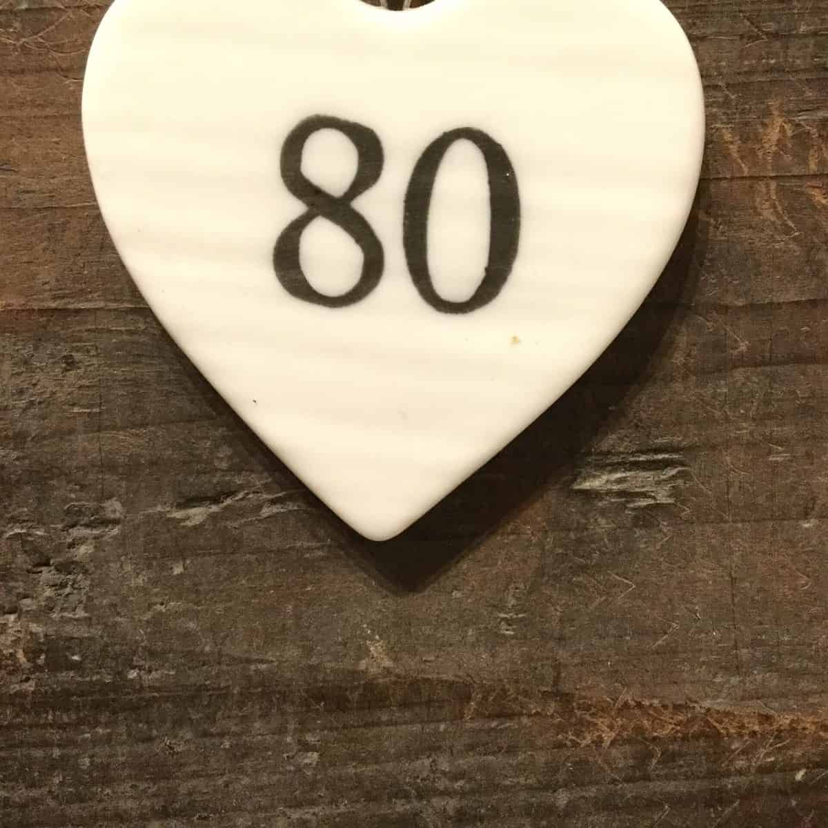 East Of India: Small White Porcelain Hanging Heart with Birthday Number in Black Writing: 80