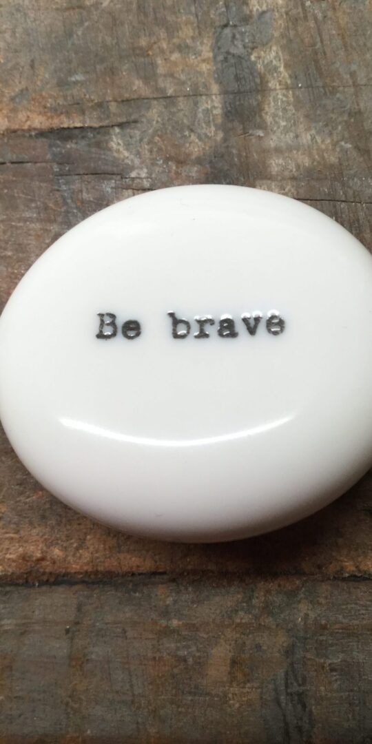 East Of India Small White Porcelain Pebble with Black Type Engraved. Saying: Be Brave