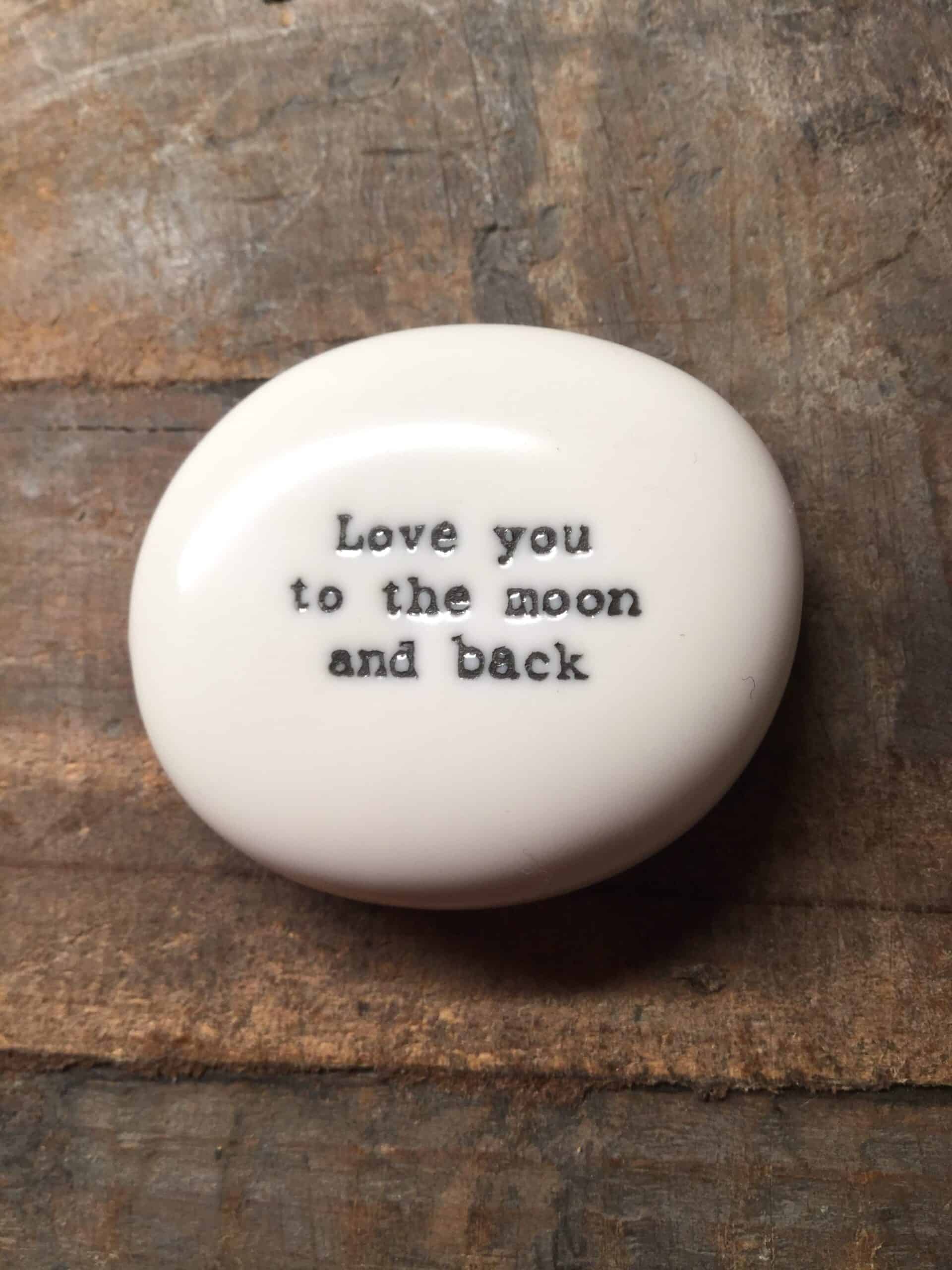 East Of India White Porcelain Pebble with Black Type Engraved. Saying: Love you To The Moon and Back.