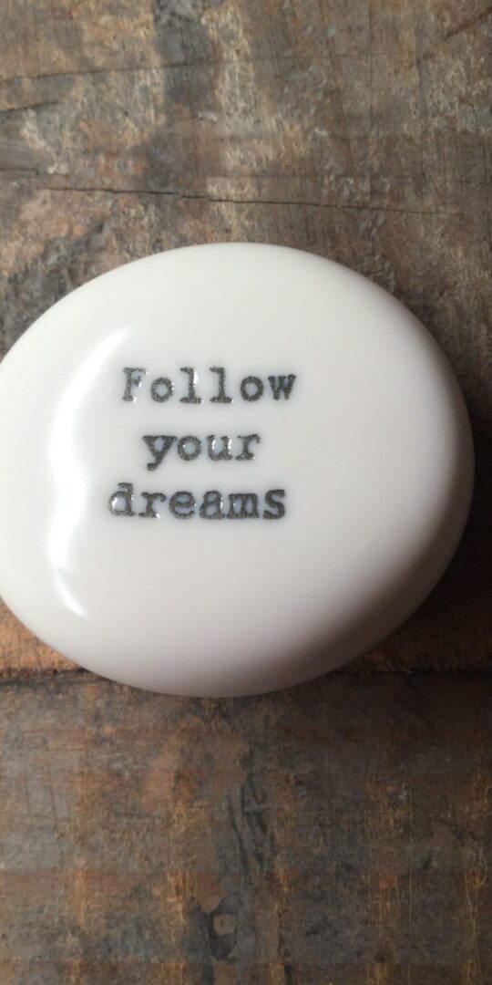 East Of India Small White Porcelain Pebble with Black Type Engraved. Saying: Follow Your Dreams