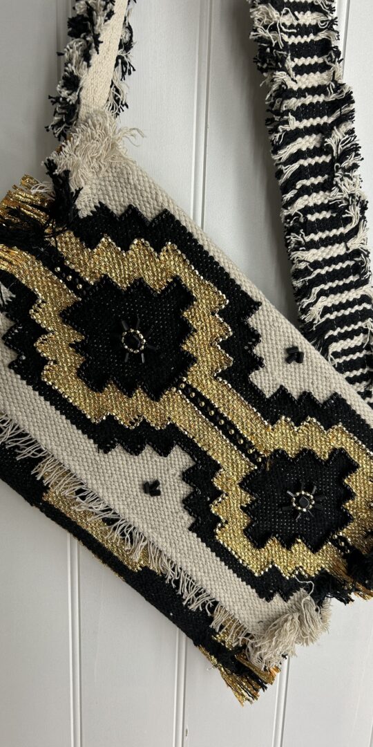 Aztec style bag with flap over closure and long strap. Black.