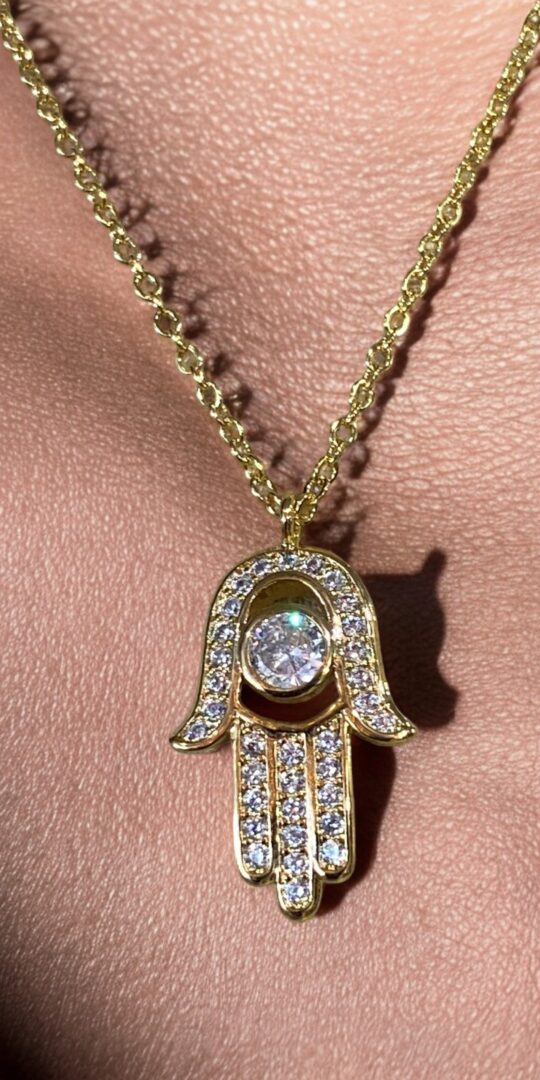 Hamsa hand necklace in gold and crystal detail.