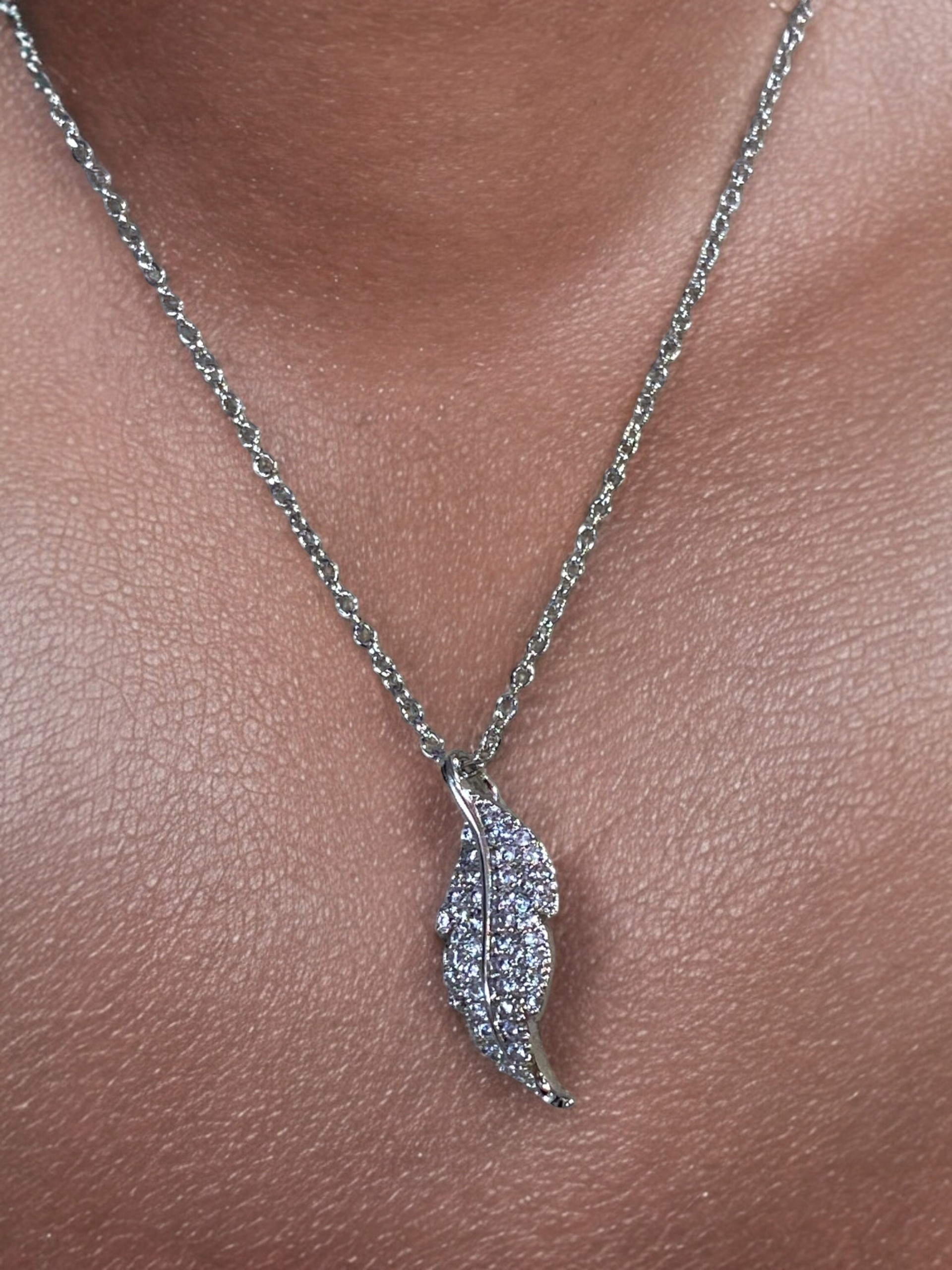 Small feather necklace embellished with crystals in silver finish.